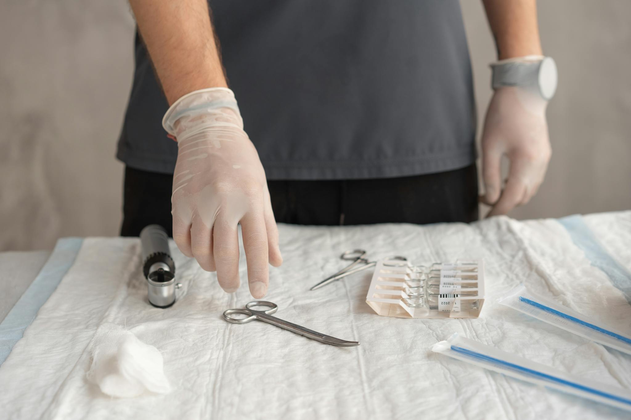 Close-up of hands in latex gloves arranging medical tools on a table.