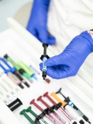 Close-up of healthcare worker's gloved hand holding a syringe in a medical setting.