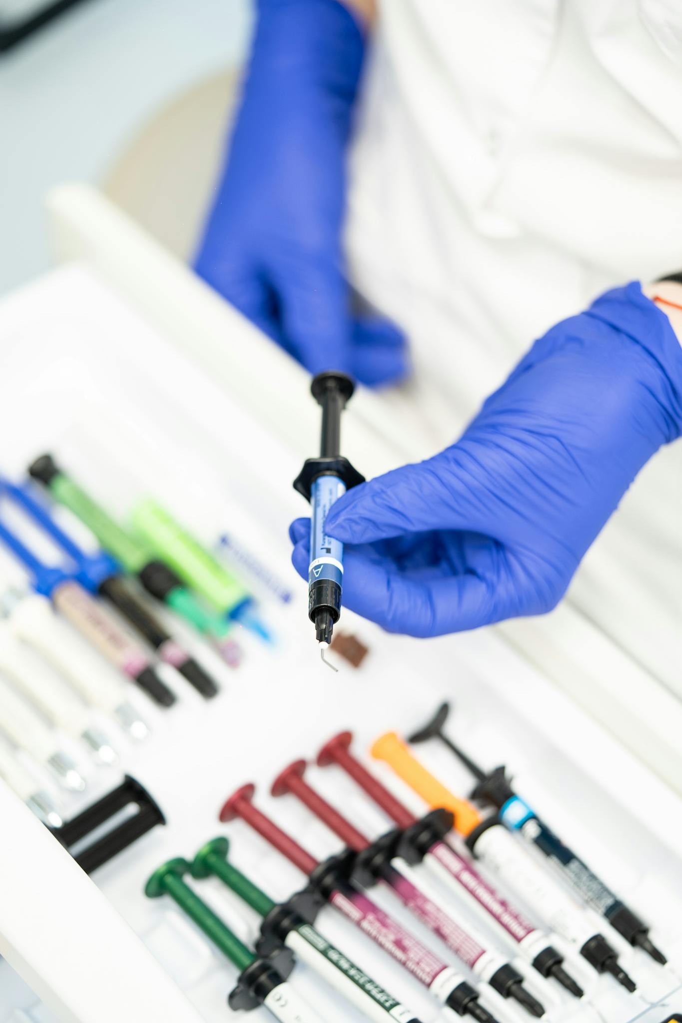 Close-up of healthcare worker's gloved hand holding a syringe in a medical setting.
