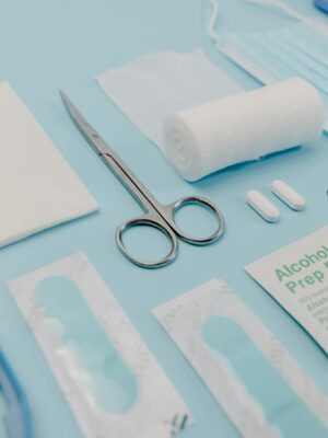 Close-up of medical supplies on a blue background, featuring bandages, pills, and scissors.