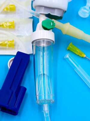 Collection of sterile medical tools including syringes and tubing against a blue backdrop.