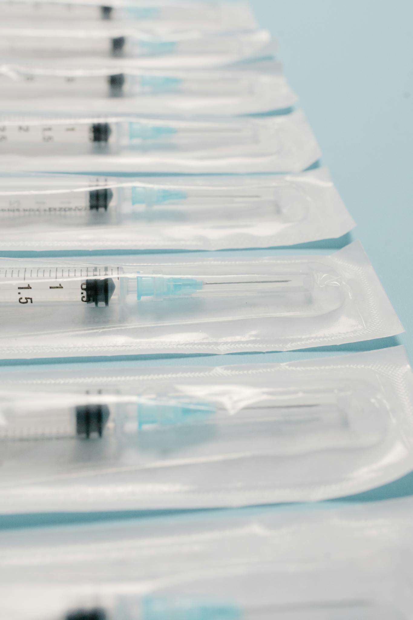 High-quality image of sterile packed syringes perfectly aligned on a blue background, highlighting medical preparedness.